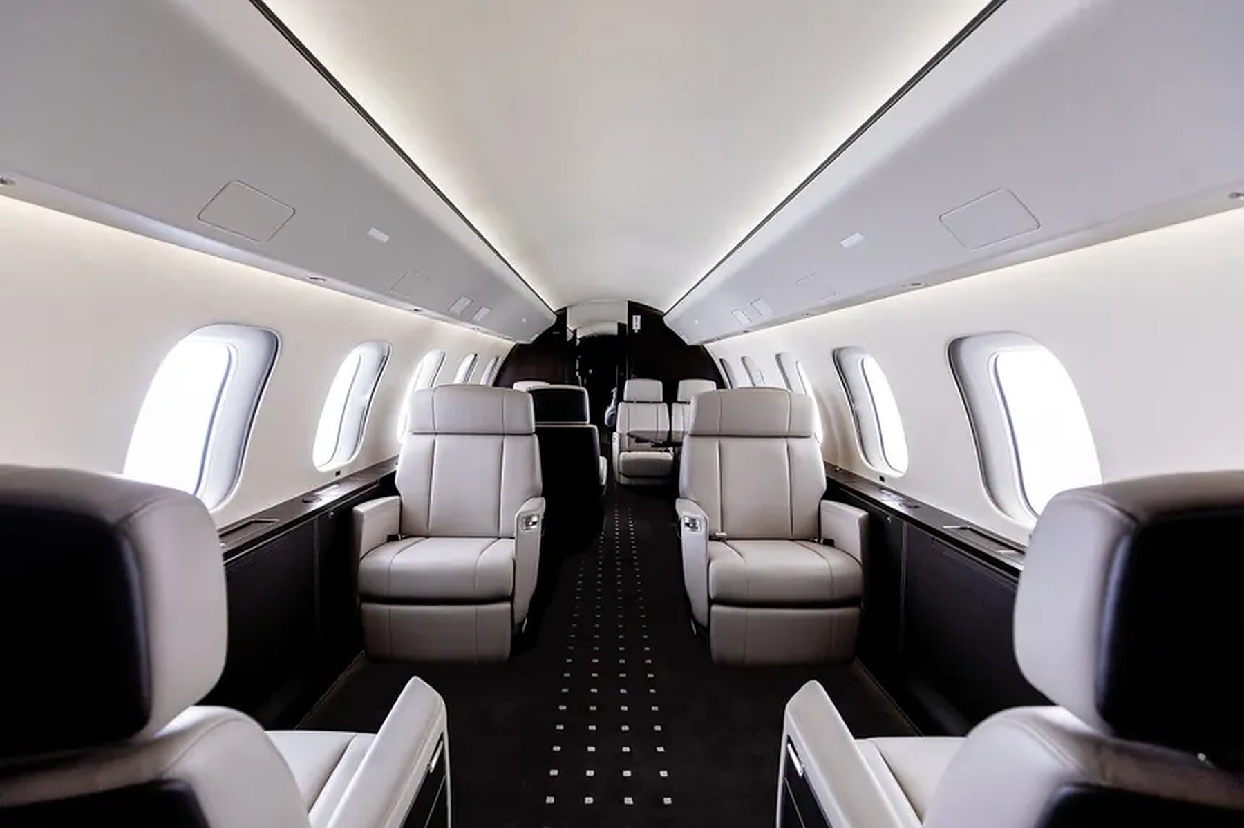 Private jet cabin with cream leather seats and oval windows